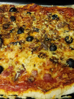 Una foto de Pizza casera de jamón, queso y anchoas