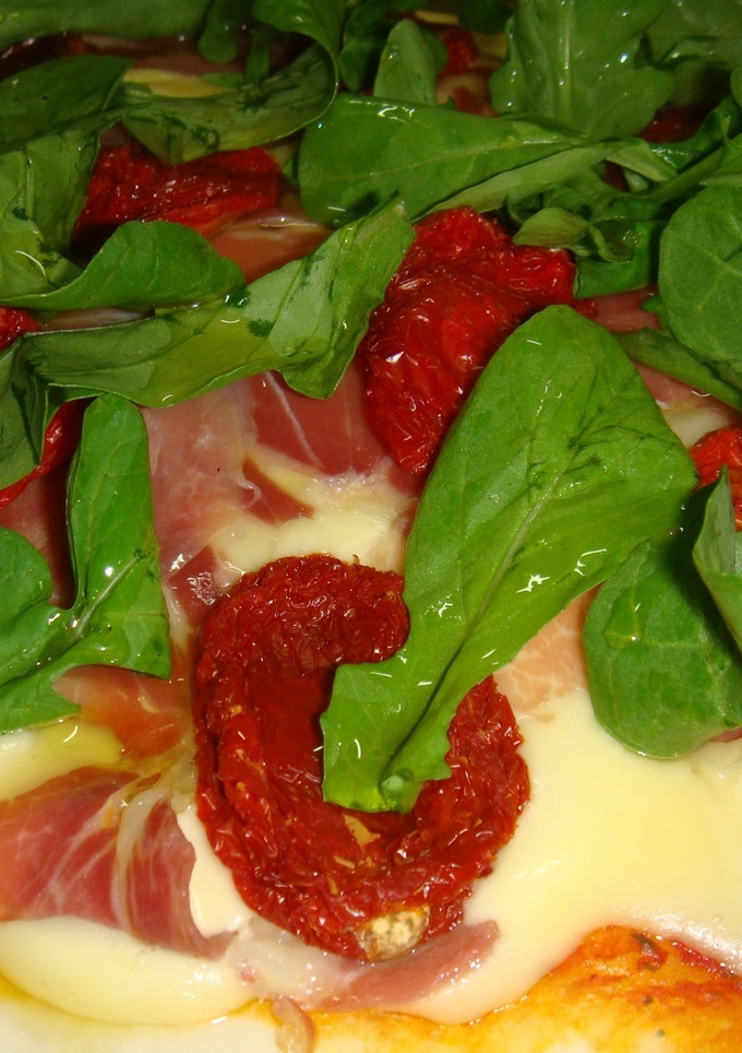 Una foto de Pizza de jamón crudo, tomatitos secos y rúcula
