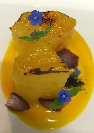 Una foto de Piña caramelizada con aroma de azafrán y coulis de mango