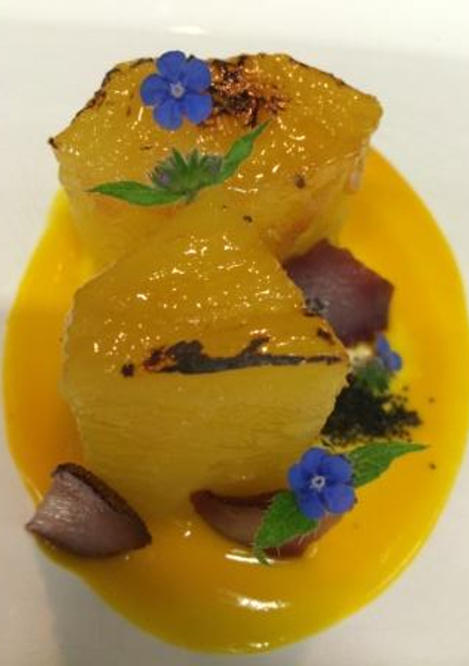Una foto de Piña caramelizada con aroma de azafrán y coulis de mango