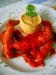 Una foto de Salchichas con tomate y puré de garbanzos