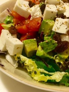 Una foto de Ensalada con tomate, queso fresco, aguacate y pasas