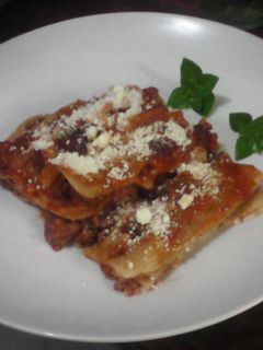 Una foto de Canelones con carne de res en salsa roja