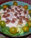 Ensalada de pollo y tomates amarillos sobre base de espinacas