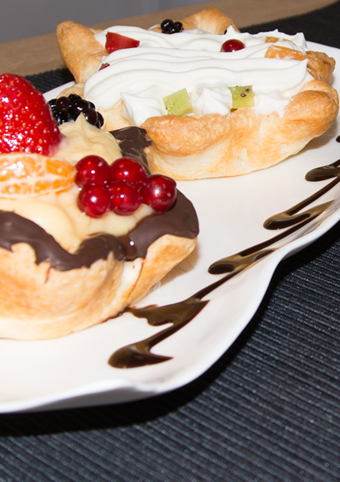 Una foto de Tartaletas de hojaldre, fruta en base de crema pastelera y nata montada