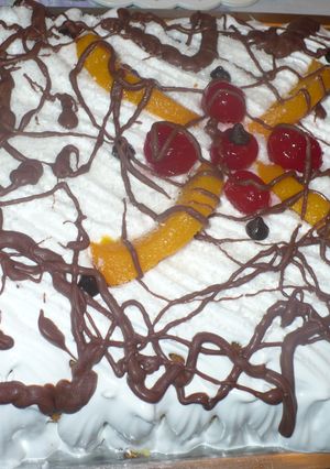 Una foto de Torta con merengue, duraznos, chocolate y cerezas