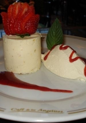 Una foto de Cheese cake de naranja con crema batida y salsa de frutilla