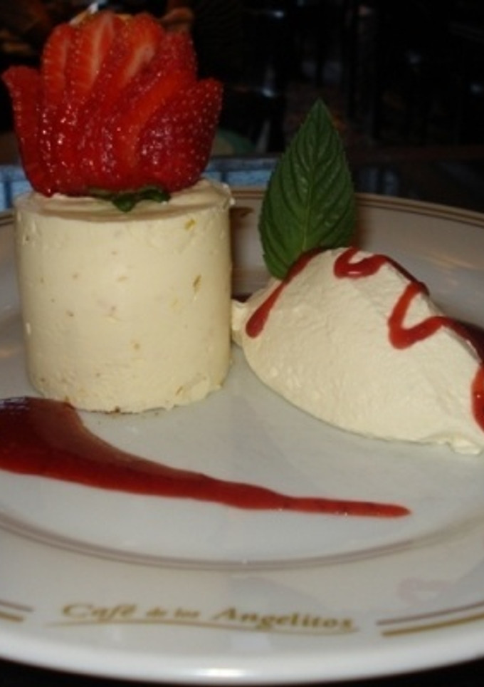 Una foto de Cheese cake de naranja con crema batida y salsa de frutilla