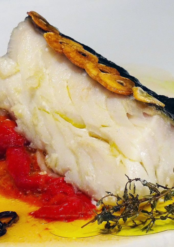 Una foto de Bacalao confitado sobre pimientos asados