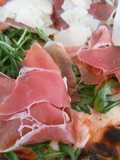 Pizza de prosciutto, rúcula y parmesano