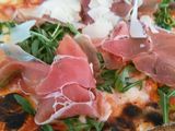 Pizza de prosciutto, rúcula y parmesano