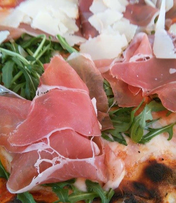 Una foto de Pizza de prosciutto, rúcula y parmesano