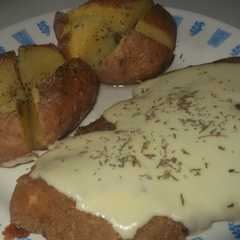 Una foto de Milanesas con queso cremoso y papas rústicas