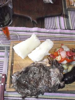 Una foto de Bifes de chorizo al ajo, con ensalada tibia, morcilla y yuca (mandioca)
