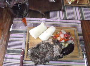 Una foto de Bifes de chorizo al ajo, con ensalada tibia, morcilla y yuca (mandioca)