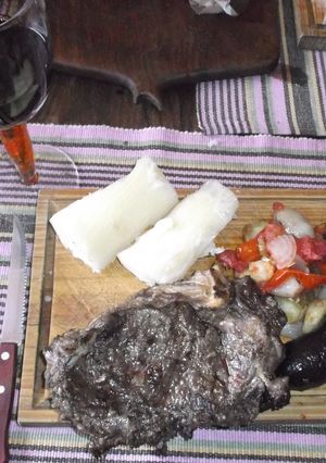 Una foto de Bifes de chorizo al ajo, con ensalada tibia, morcilla y yuca (mandioca)