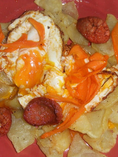Una foto de Huevos rotos con patatas, chips de zanahoria y chorizo de Ronda