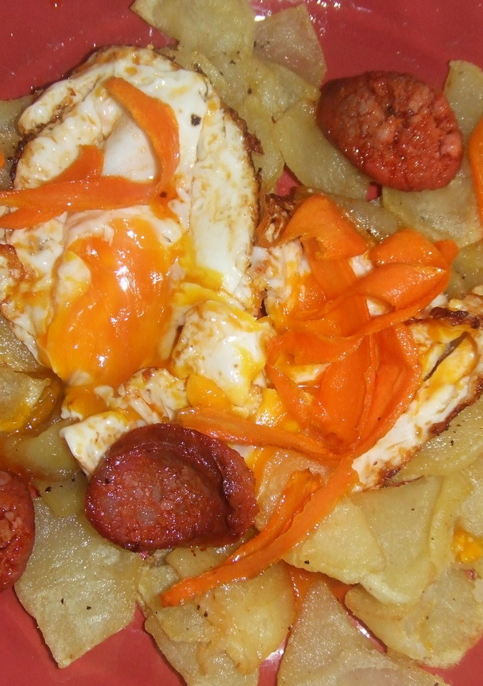 Una foto de Huevos rotos con patatas, chips de zanahoria y chorizo de Ronda