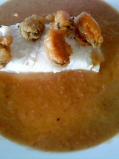 Una foto de Merluza en salsa de cebolla con mejillones en tempura