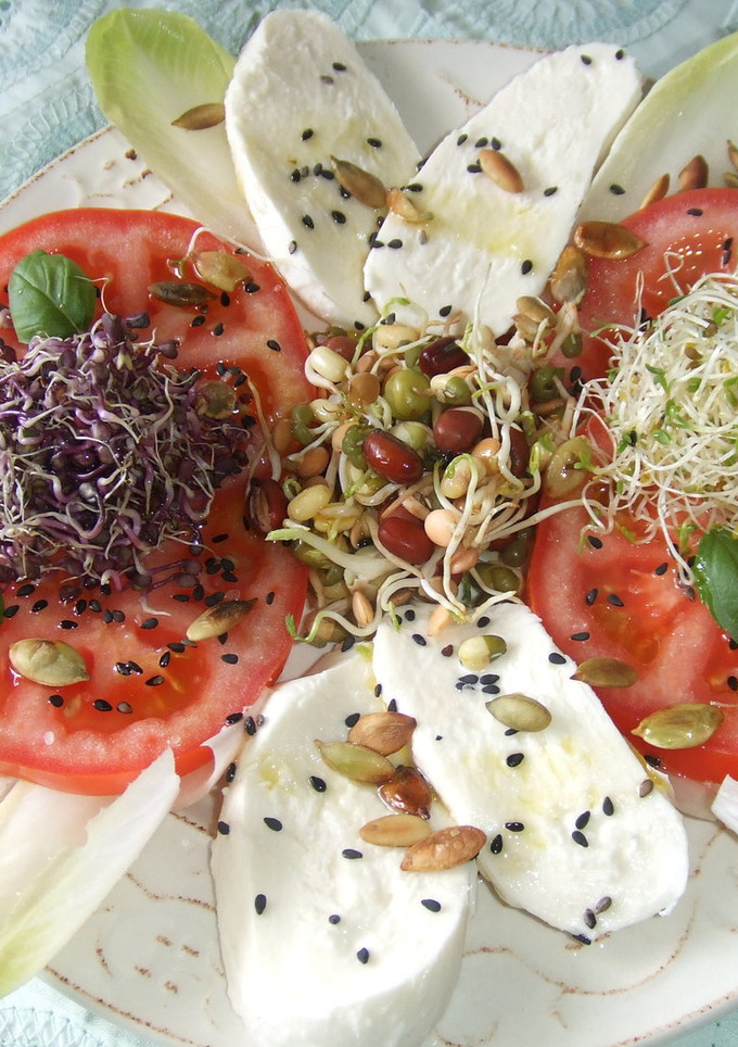 Una foto de Ensalada de tomate y mozzarella con brotes y semillas