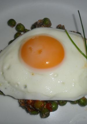 Una foto de Huevo frito sobre colchón de arvejas