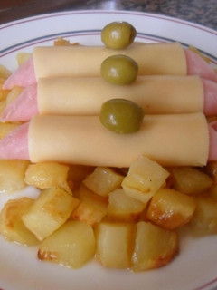 Una foto de Rollitos de jamón y queso sobre dados de patatas al horno