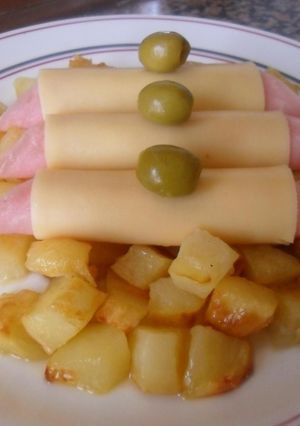 Una foto de Rollitos de jamón y queso sobre dados de patatas al horno