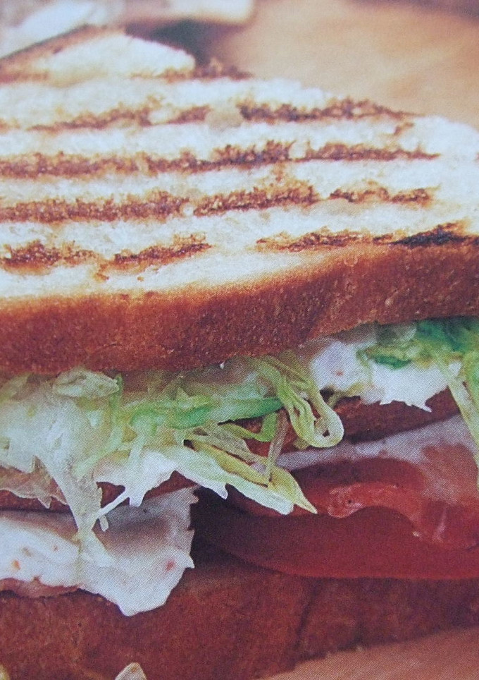 Una foto de Sándwich de pavita con lechuga, bacón y queso