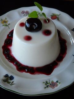 Una foto de Panna cotta de coco con coulis de cerezas