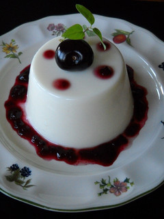 Una foto de Panna cotta de coco con coulis de cerezas
