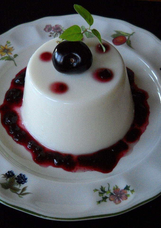 Una foto de Panna cotta de coco con coulis de cerezas