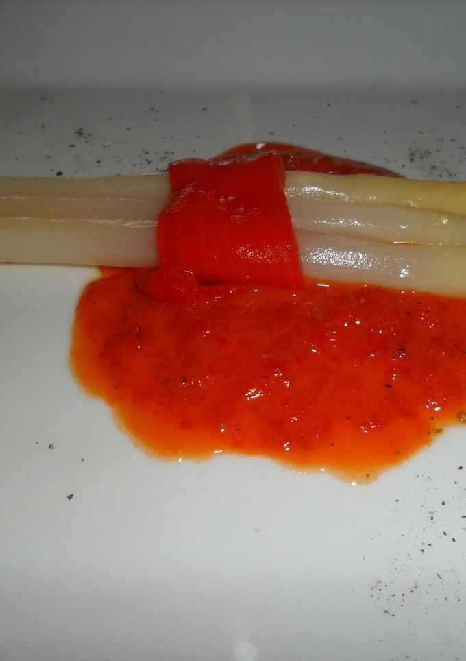 Una foto de Espárragos blancos sobre salsa de morrones