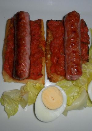 Una foto de Salchicha de cerdo sobre tostadas con vinagreta de tomates frescos