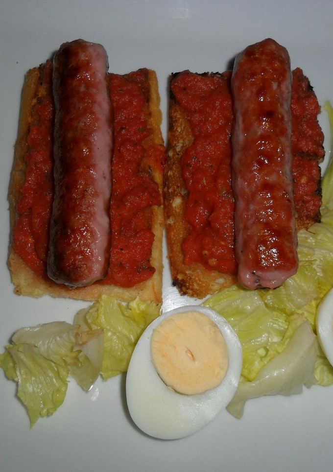 Una foto de Salchicha de cerdo sobre tostadas con vinagreta de tomates frescos