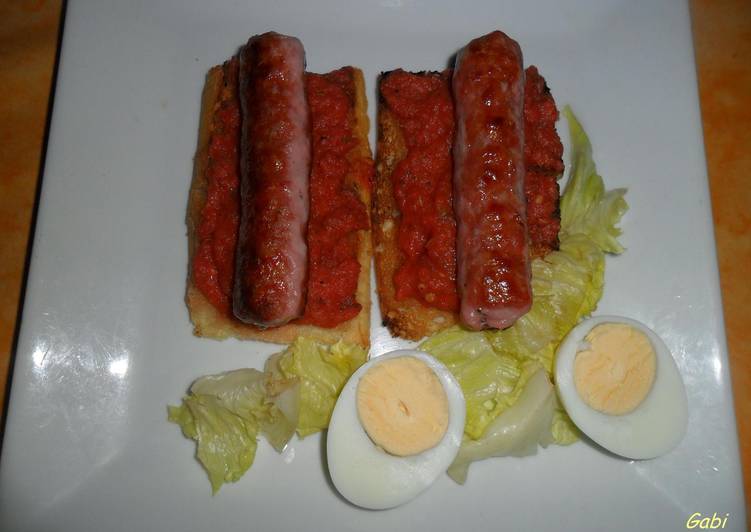 Salchicha de cerdo sobre tostadas con vinagreta de tomates frescos