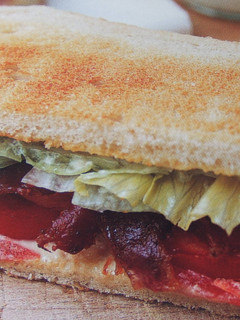 Una foto de Sándwich tostado de bacón ahumado con tomate y lechuga