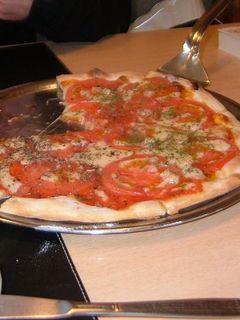 Una foto de Pizza con tomates frescos y albaca