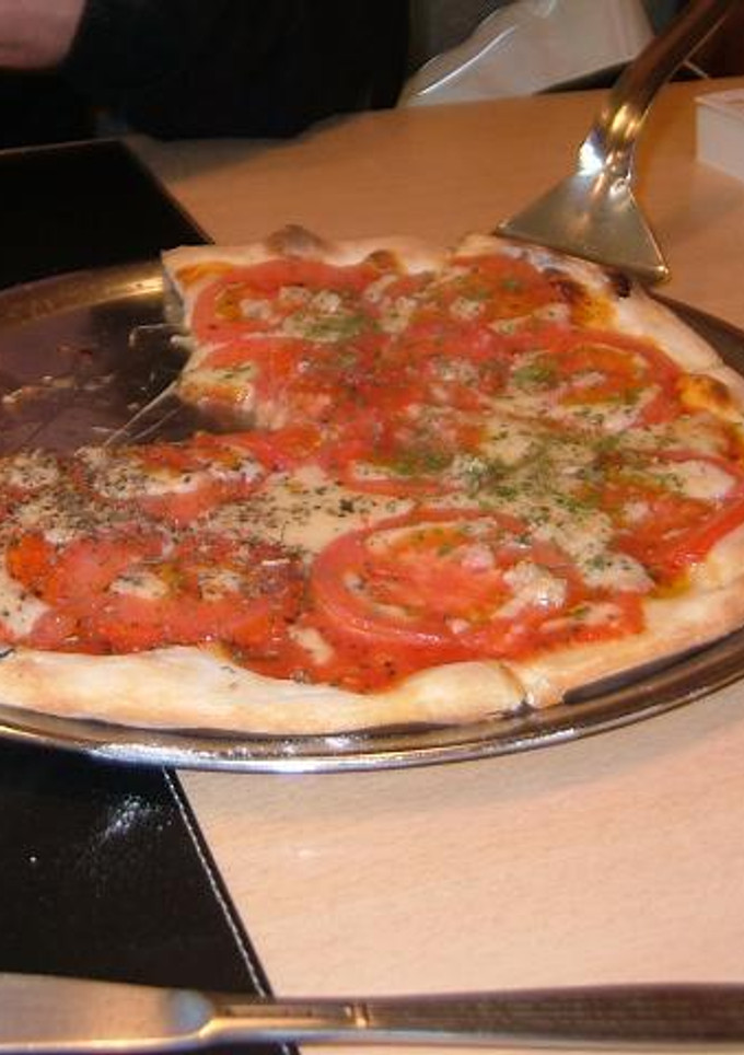 Una foto de Pizza con tomates frescos y albaca