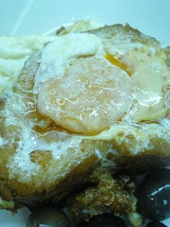 Una foto de Pan con huevo frito y aceitunas