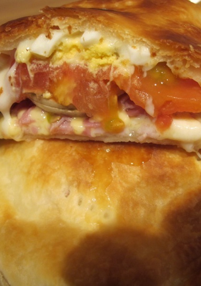 Una foto de Calzone relleno con jamón, queso y aceitunas