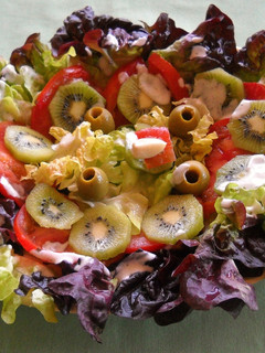 Una foto de Ensalada de lechuga hoja de roble y kiwis con salsa de queso y ajo