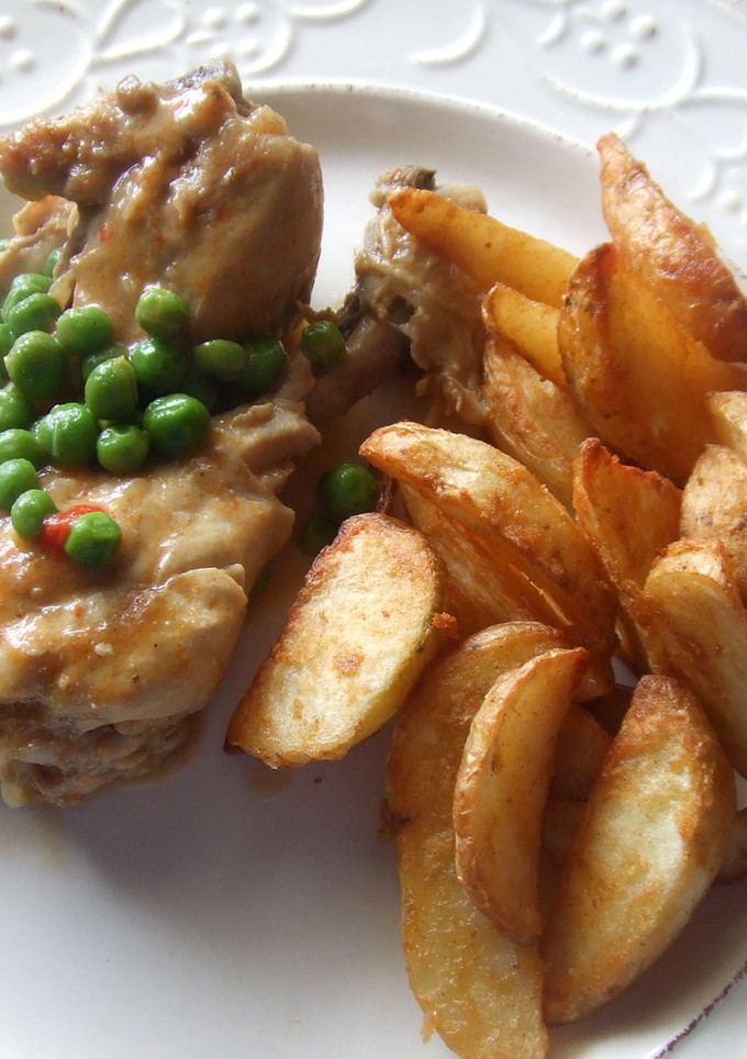 Una foto de Muslitos de pollo guisados con guisantes y gajos de patatas