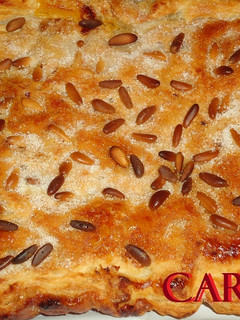 Una foto de Coca de hojaldre con crema, almendras y piñones