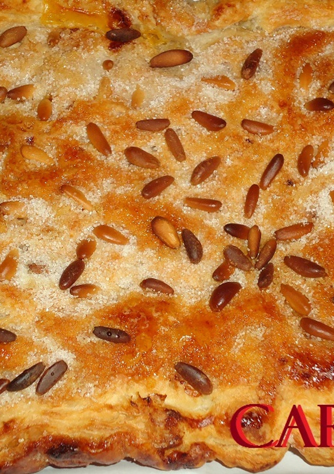 Una foto de Coca de hojaldre con crema, almendras y piñones
