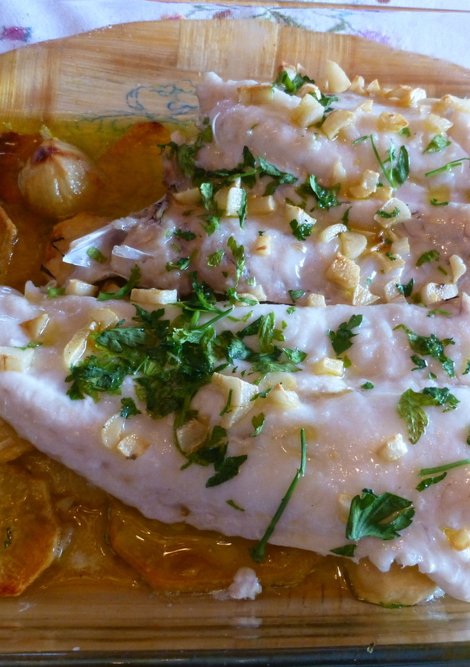 Una foto de Merluza al horno con ajitos, perejil y patatas panaderas