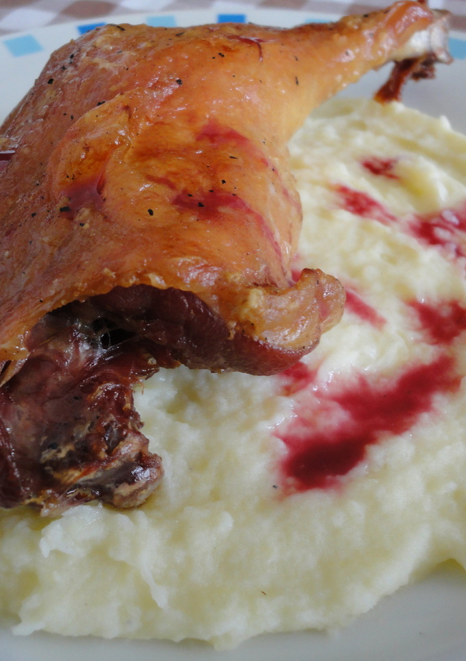 Una foto de Confit de pato con puré de patata y salsa de frutos rojos
