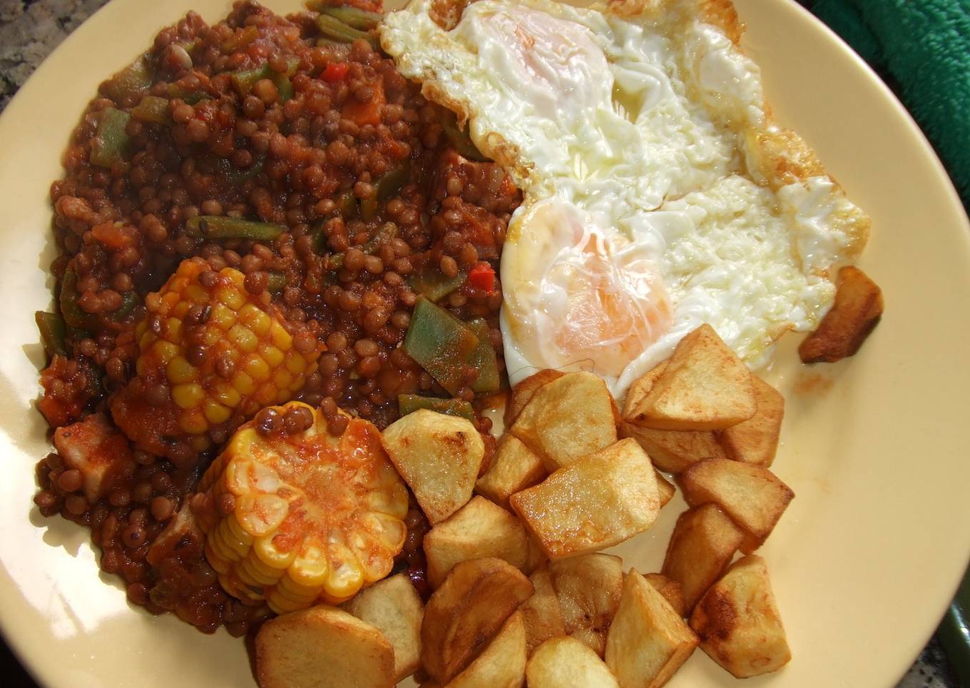 Plato de lentejas, patatas y huevos fritos con choclo (mazorca de maíz)