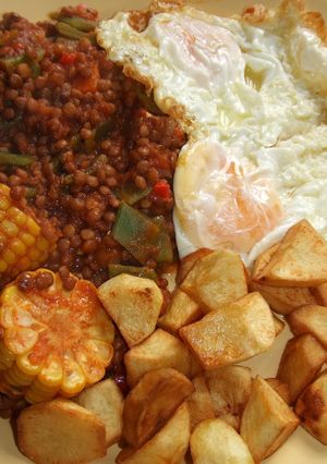 Una foto de Plato de lentejas, patatas y huevos fritos con choclo (mazorca de maíz)