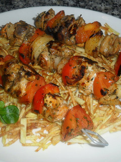 Una foto de Brochetas de pollo sobre patatas paja