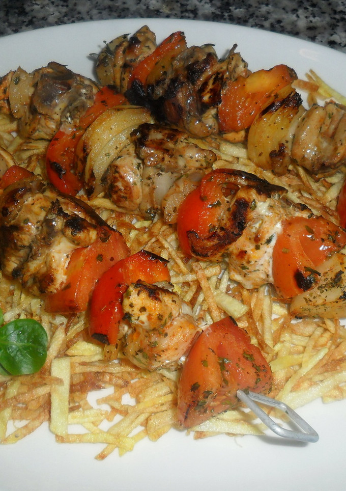 Una foto de Brochetas de pollo sobre patatas paja